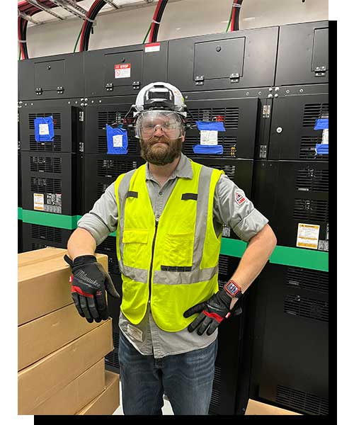 Mitsubishi Electric technician on site in front of equipment in proper PPE.