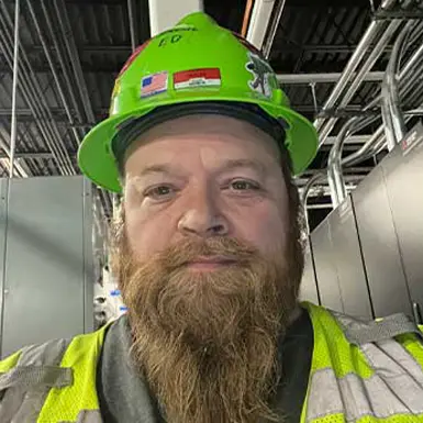 Field tech in green hard hat and yellow safety vest.