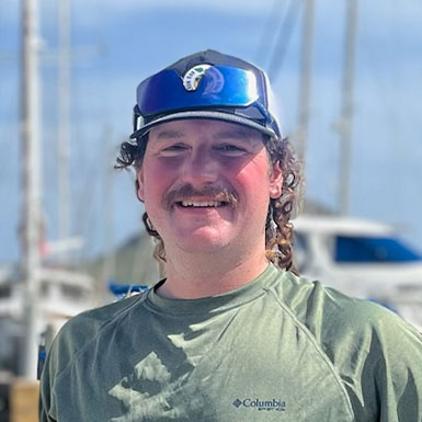 Man smiling outside in front of boat.